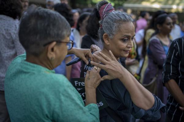 A journalist pins a small placard on the dress of writer and activist Arundhati Roy, right, during a protest at press club of India in New Delhi on Oct 4. Photo: AP 
