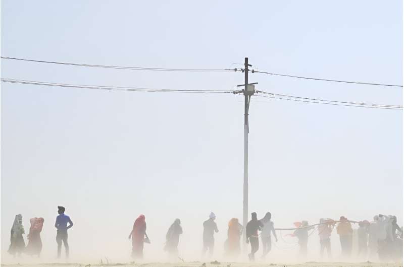 People walk through a dust storm on a hot summer day in India in April 2023.